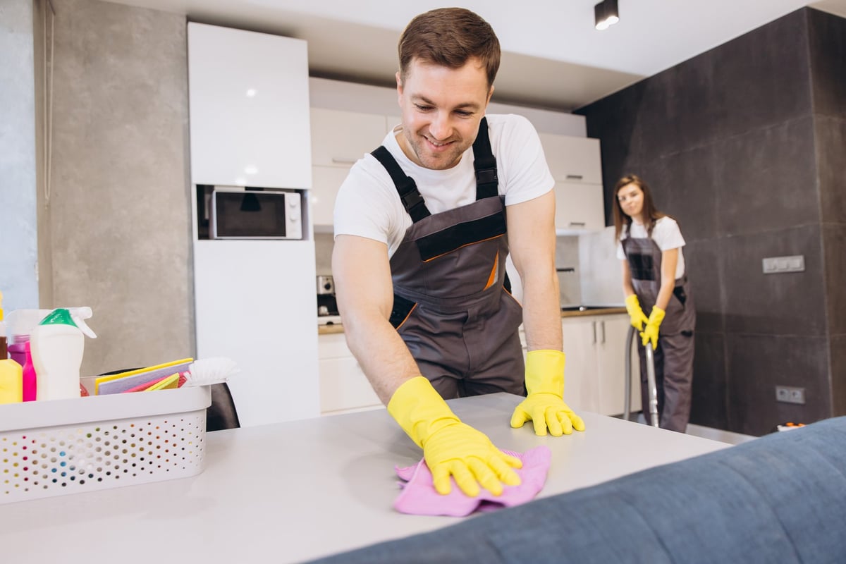 Cleaning company employees in uniforms cleaning a kitchen table and floor